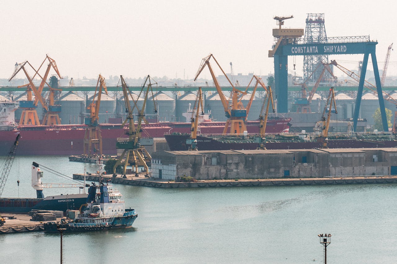A busy scene at Constanta Shipyard, Romania, featuring cranes and cargo ships in the harbor.